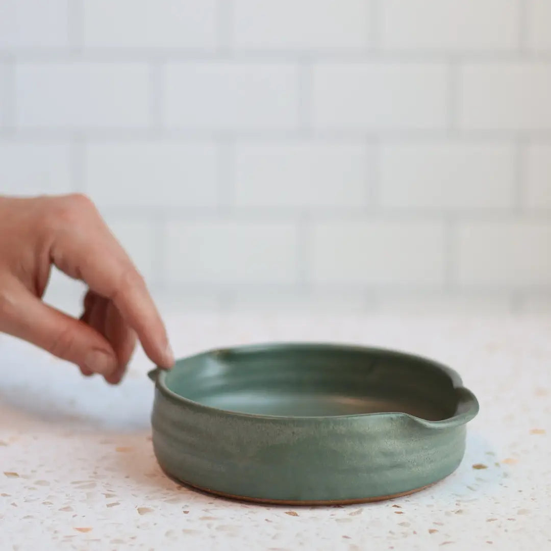 Wheel-thrown Brie Baker in iridescent Lagoon glaze, showing depth and flowing teal-blue colors
